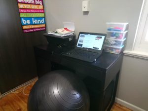 Computer on small desk with gym ball instead of a chair.